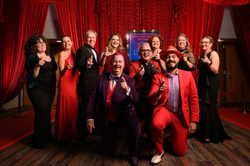 Ten people in formal dress posing in front of red draping.